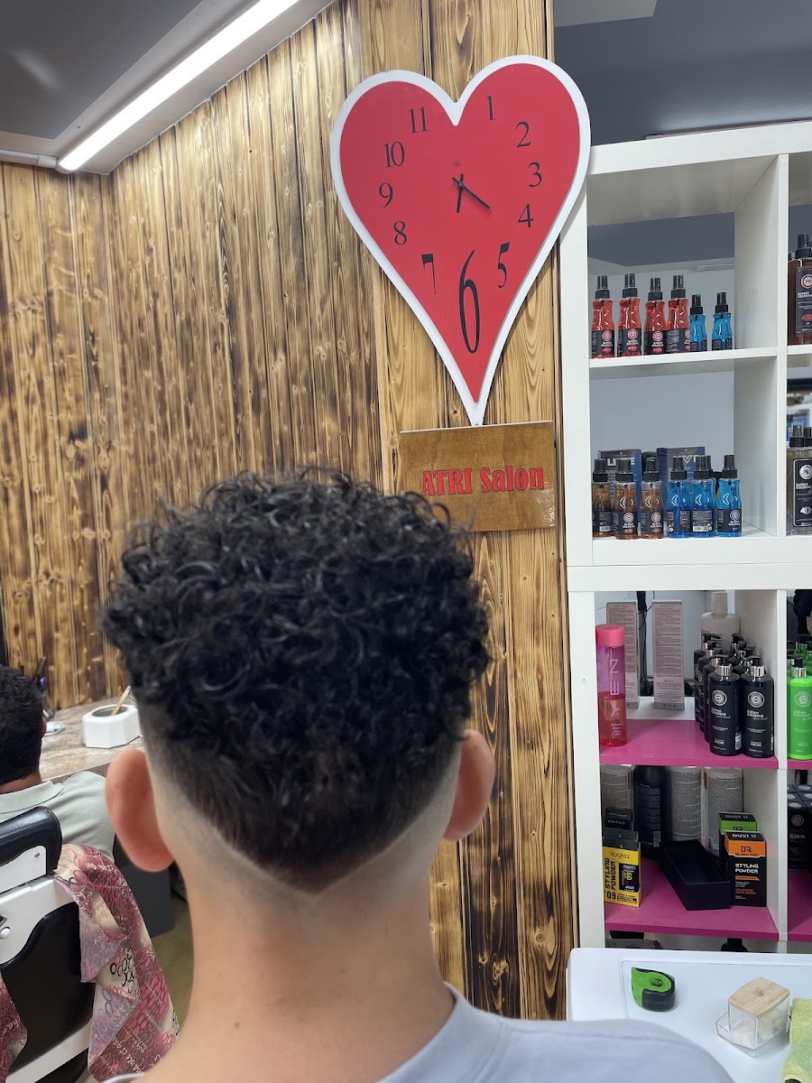 Frisch geschnittener Fade mit Locken, Atri Salon Schild im Hintergrund